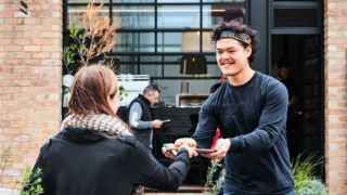 Man giving food to customer outside cafe