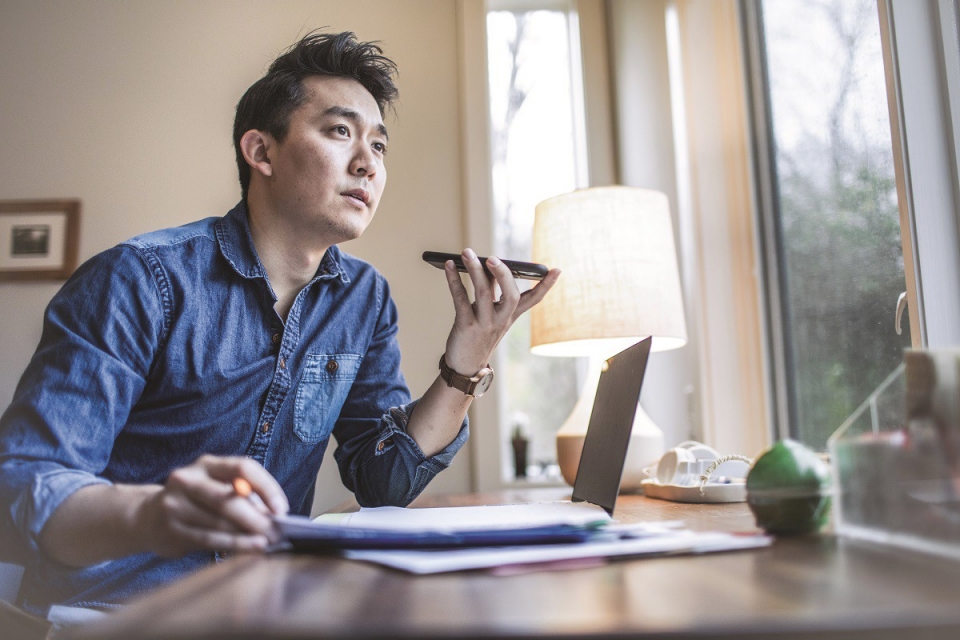 man in blue shirt at desk speaking on mobile phone