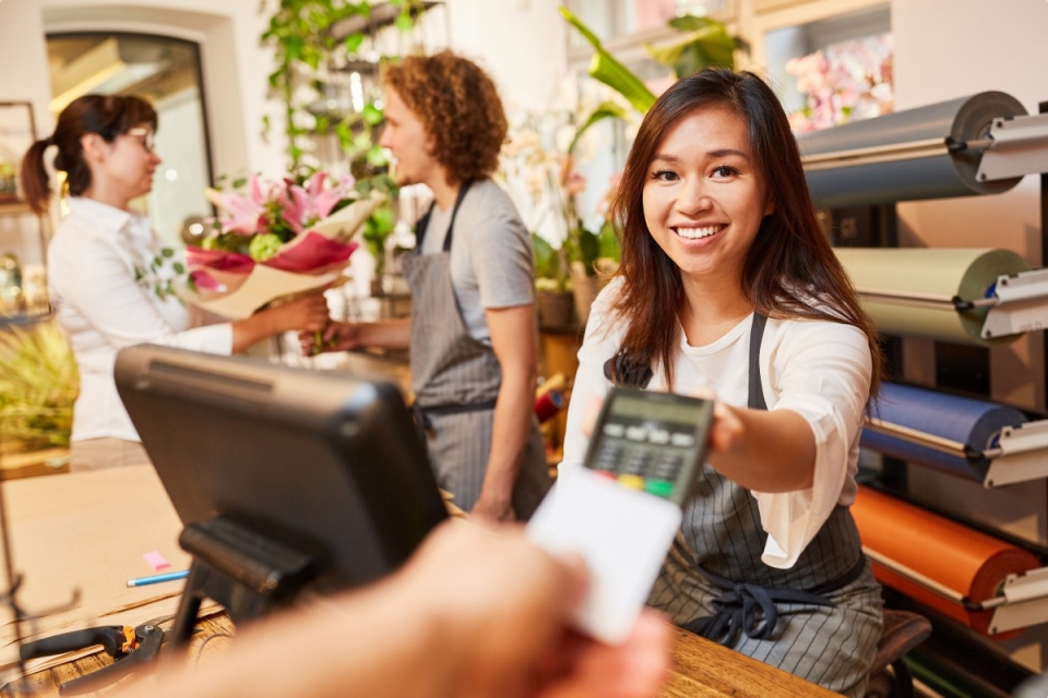 Woman in flower shop taking card payment with EFTPOS machine