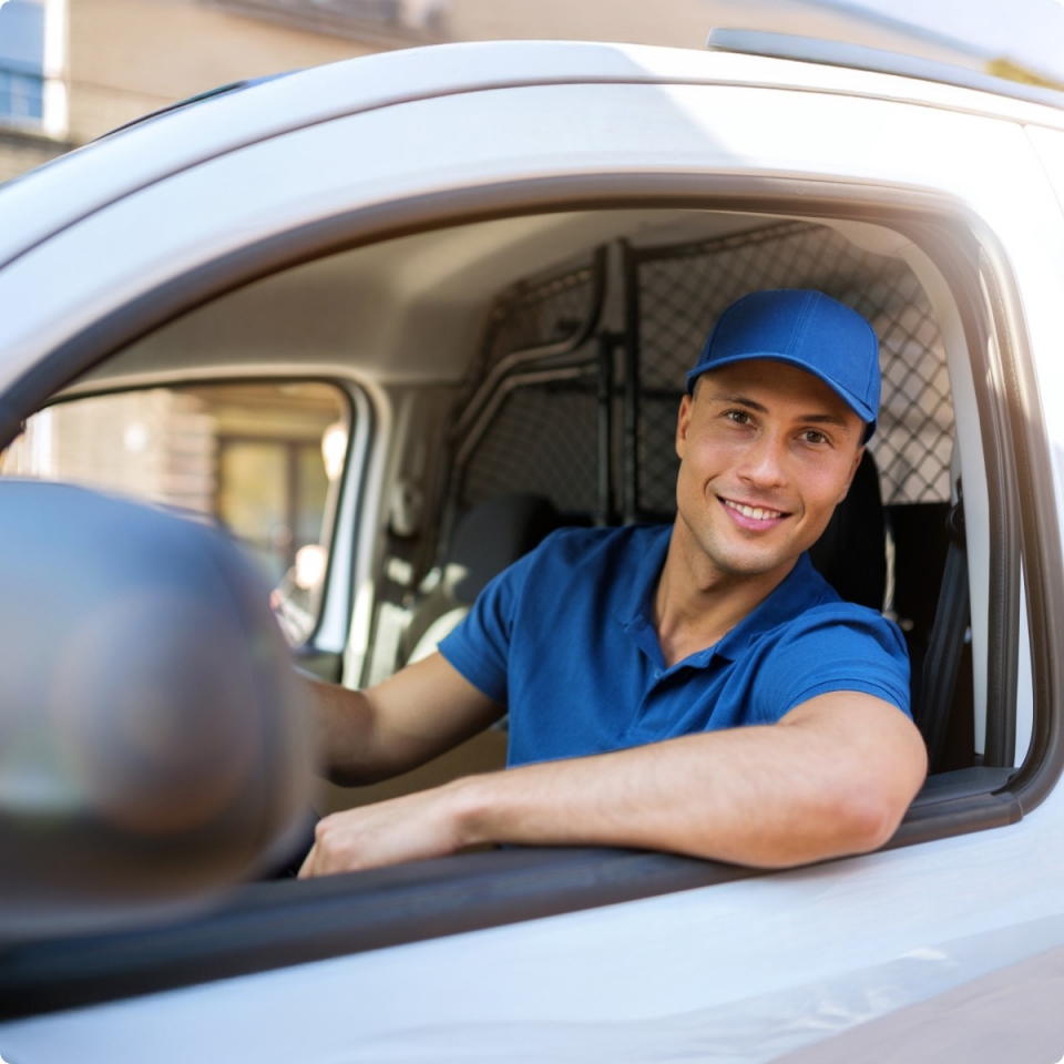 Driver in van smiling wearing blue top and cap