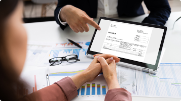 A woman's folded hands in front of an ipad with financial data on it