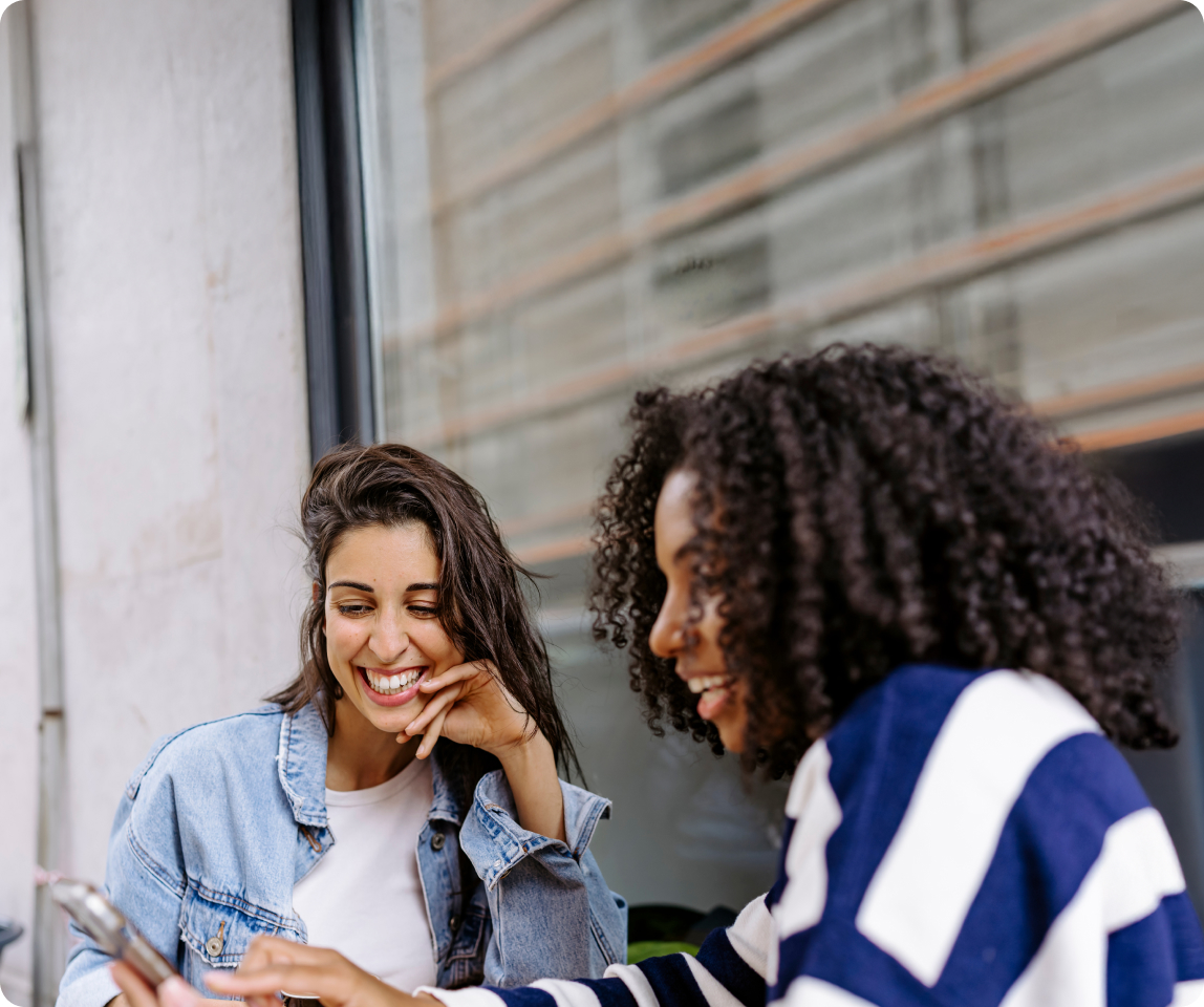 Two girls were sitting and laughing happily with each other.